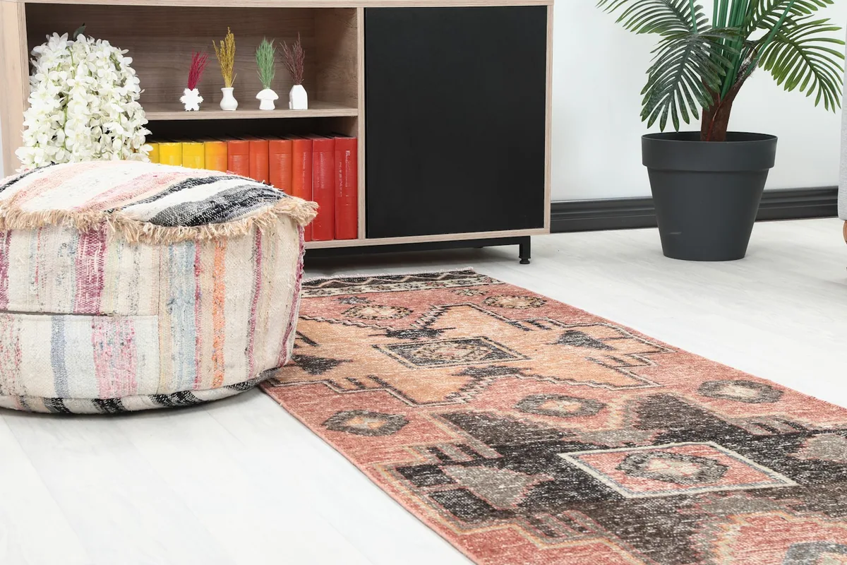 Close-up view of the runner rug's pattern alongside a decorative ottoman and cabinet