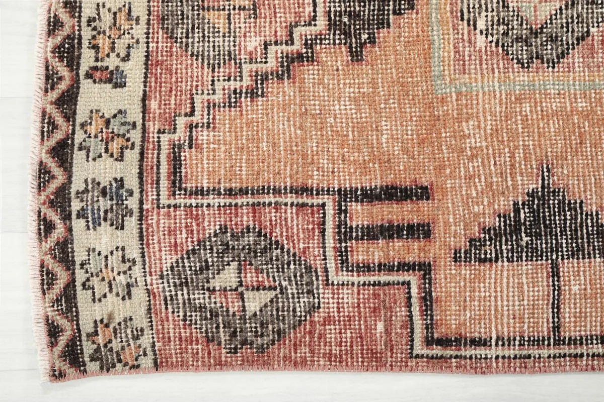 Detailed view of the rug's border and corner, showing the wool texture and design