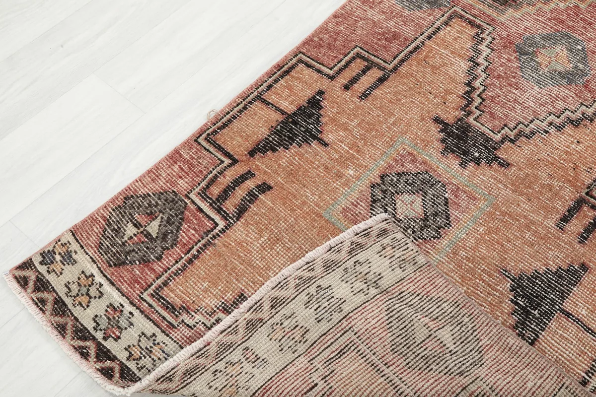 View of the rug's low pile and cotton foundation, with a corner folded back