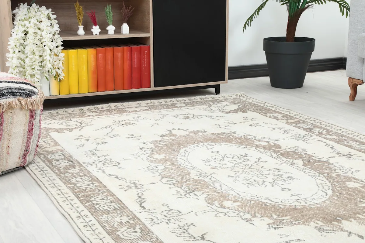 Close-up of the ivory rug's central floral medallion and border within a room setup, showing surrounding decor