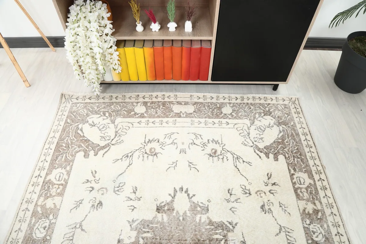 Detail view of the top section of the rug, showing floral motifs and border next to a cabinet