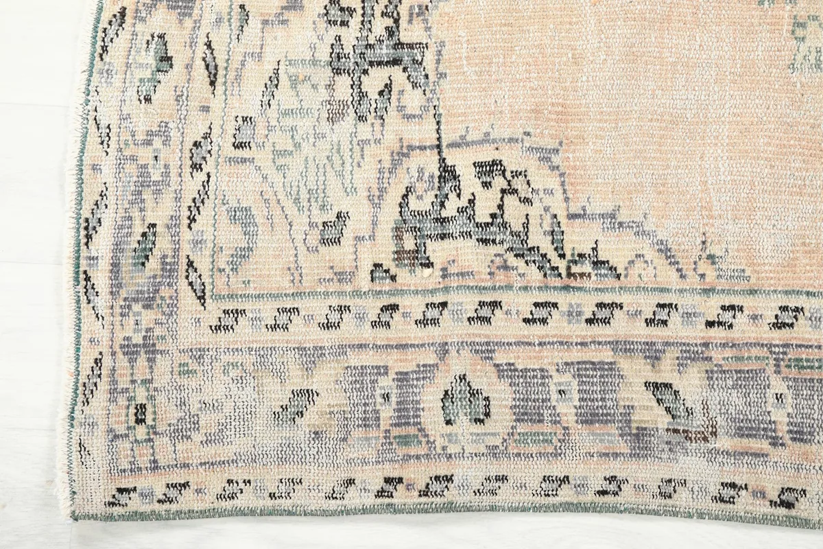 Edge view of the rug, showing the detailed gray and beige border pattern