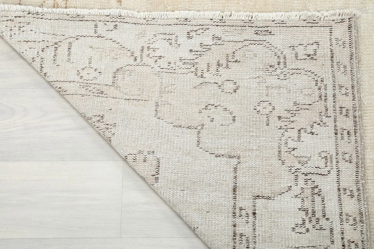 Close-up of the back of the rug, showing the cotton foundation and the tightly knotted wool pile.