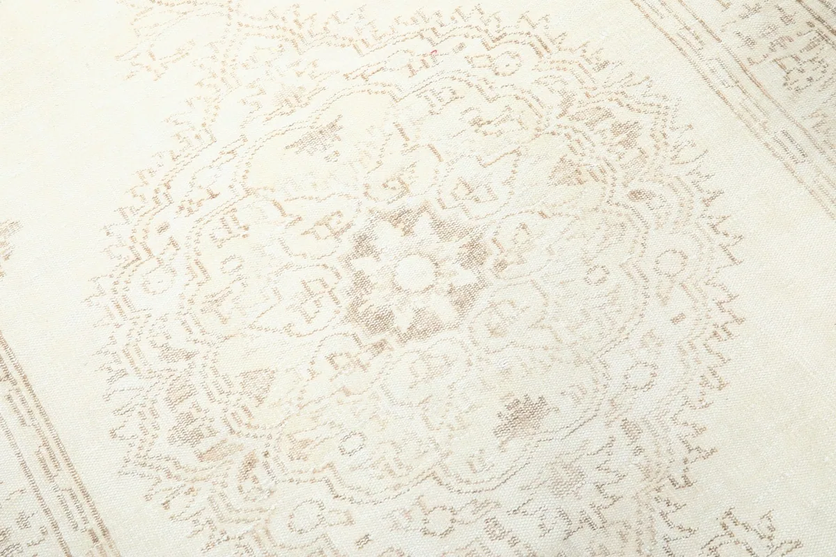 Detailed close-up of the central medallion motif in beige and tan on the cream field.