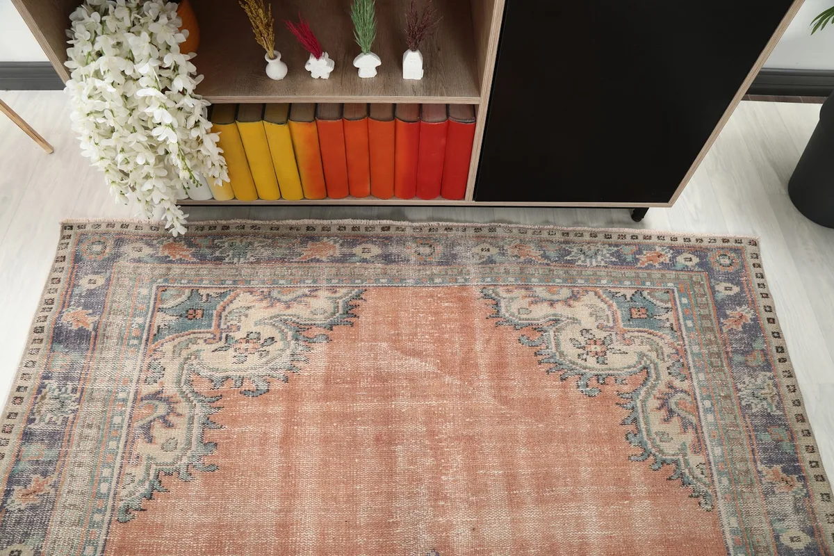 Detail view of the rug's upper border and corner next to a cabinet in a room