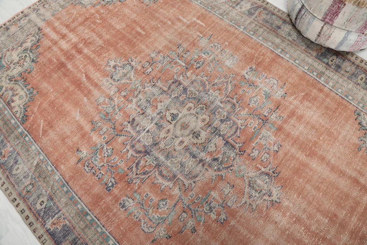 Close-up of the central medallion motif in blue, gray, and beige on the rust field