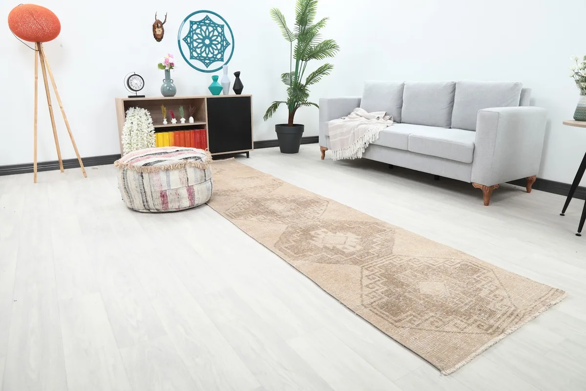 Angle view of the tan and brown geometric runner rug in a contemporary room with a gray sofa.