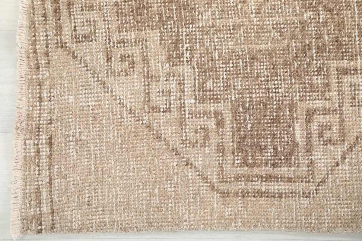 Tight close-up showing the low pile texture and intricate weaving of the vintage tan and brown runner rug.