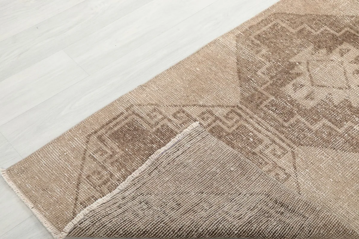 Corner of the Anatolian runner rug folded back, revealing the wool pile and cotton foundation.