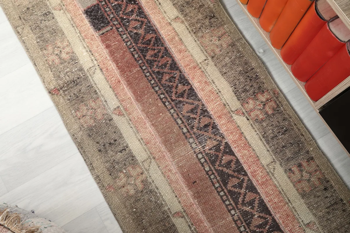 Angled close-up of the rug's striped and geometric motifs in beige, rust, and charcoal.