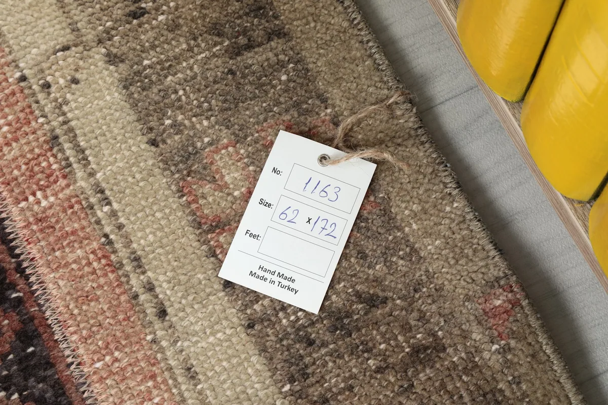 Photo of the product tag attached to the rug, displaying its size in centimeters and handmade origin.
