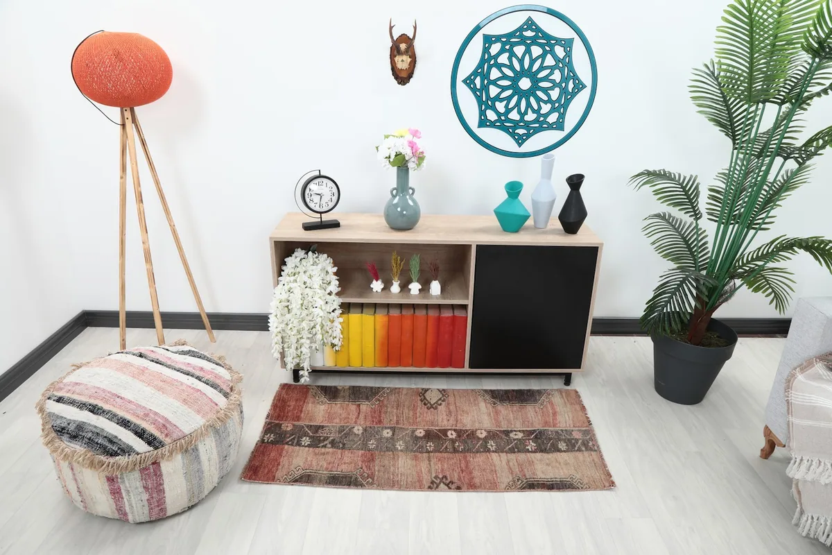 Rose and brown vintage rug placed in a modern living space with a console table and pouf