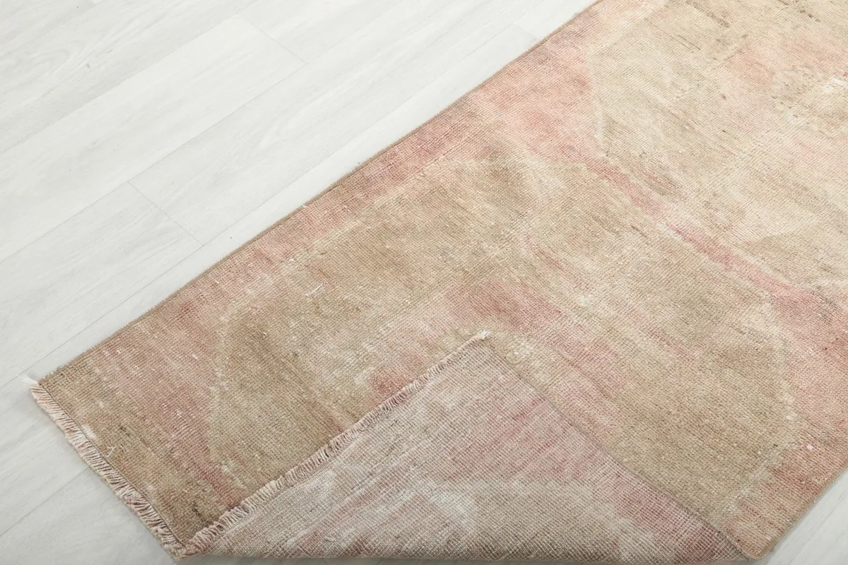 Corner of the runner rug folded back to reveal the back of the rug and the foundation