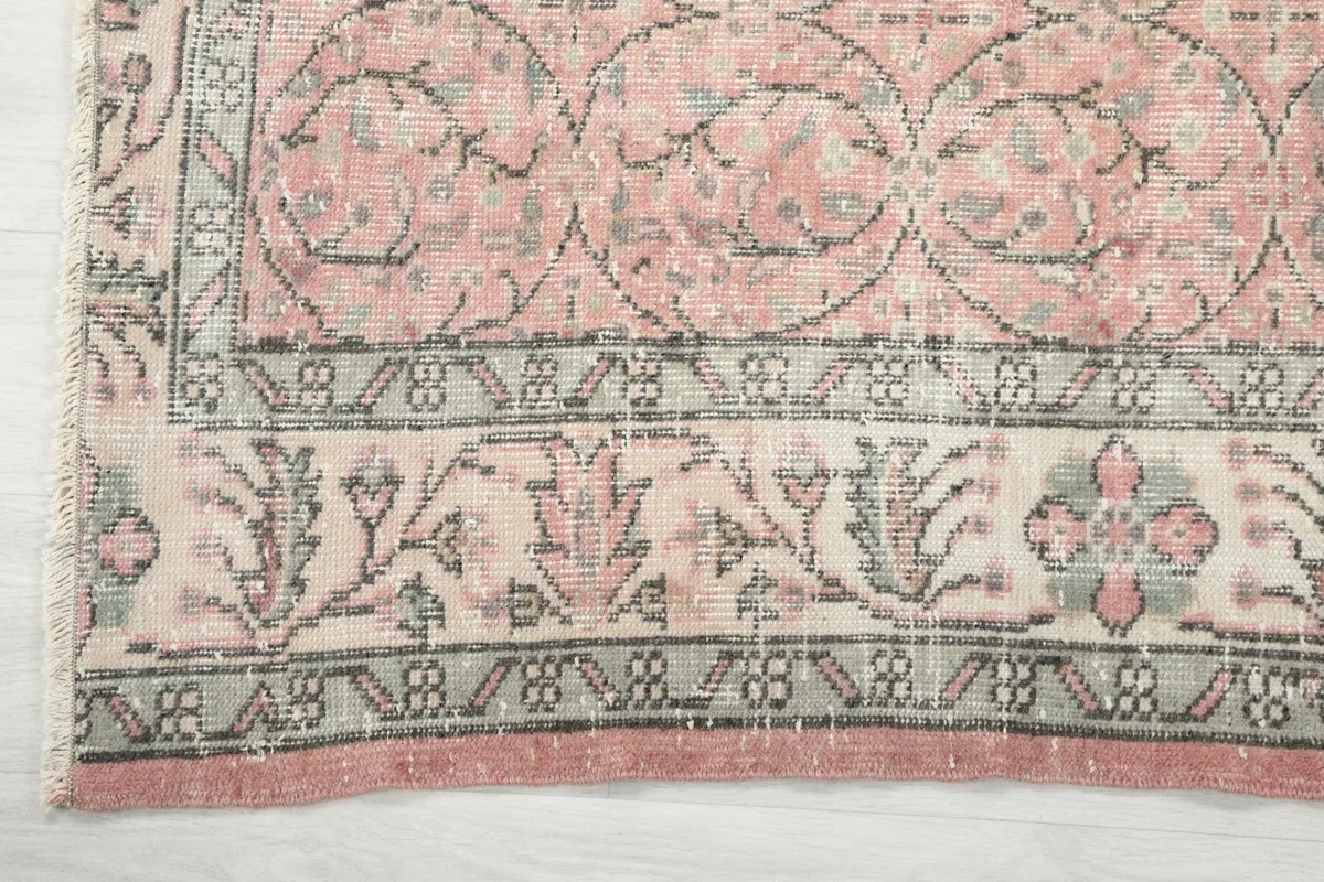 Detailed view of the rug's gray and ivory border with floral elements and fringe