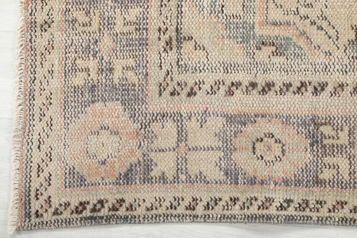 Detailed view of the intricate gray and ivory border pattern and edge of the rug