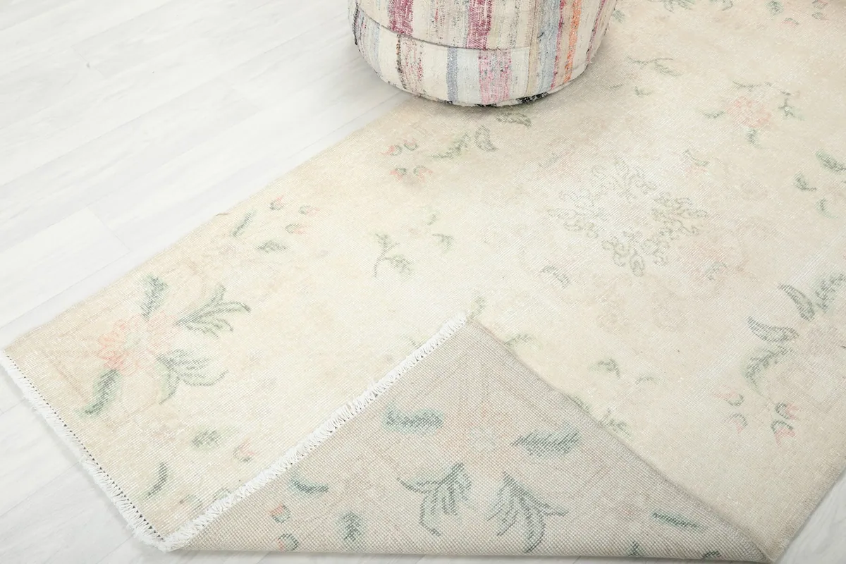 Corner of the rug folded back, revealing the hand-knotted cotton foundation and wool pile