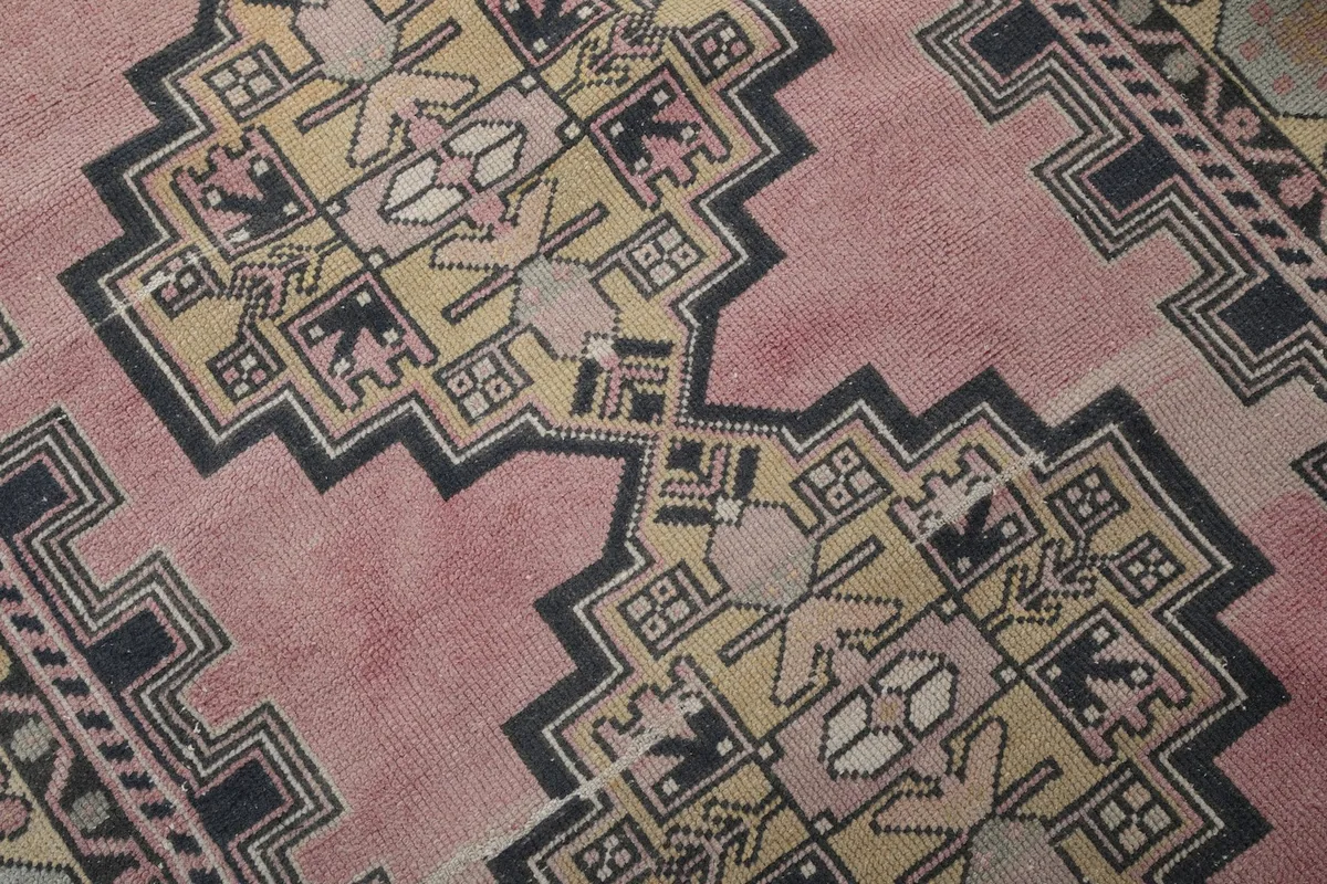 Close-up detail of the central geometric medallion and surrounding tribal motifs in navy, yellow, and rose