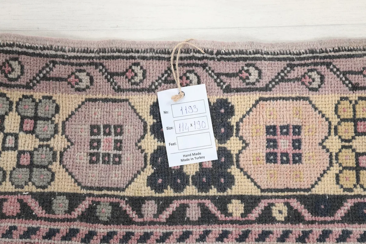 Detail of the rug's border with a tag showing the hand-made origin and dimensions