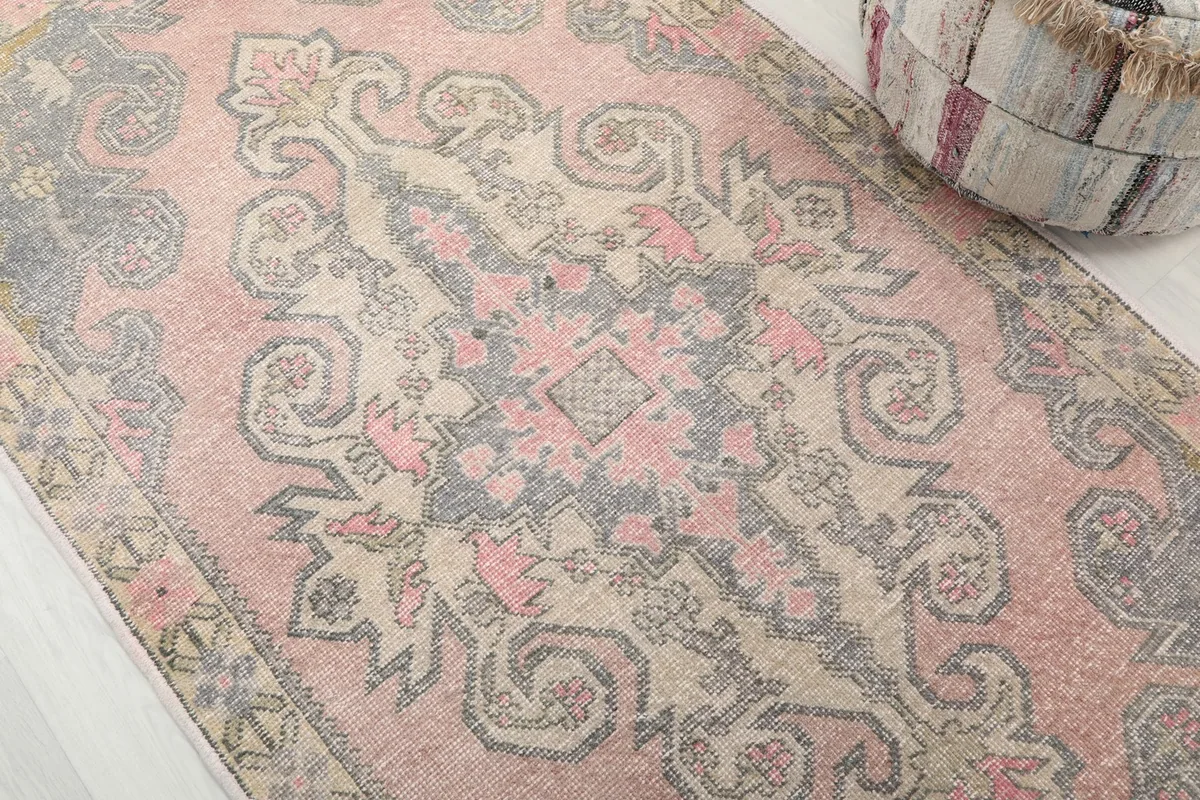 Detailed view of the rose and gray vintage rug's central medallion and surrounding geometric motifs.
