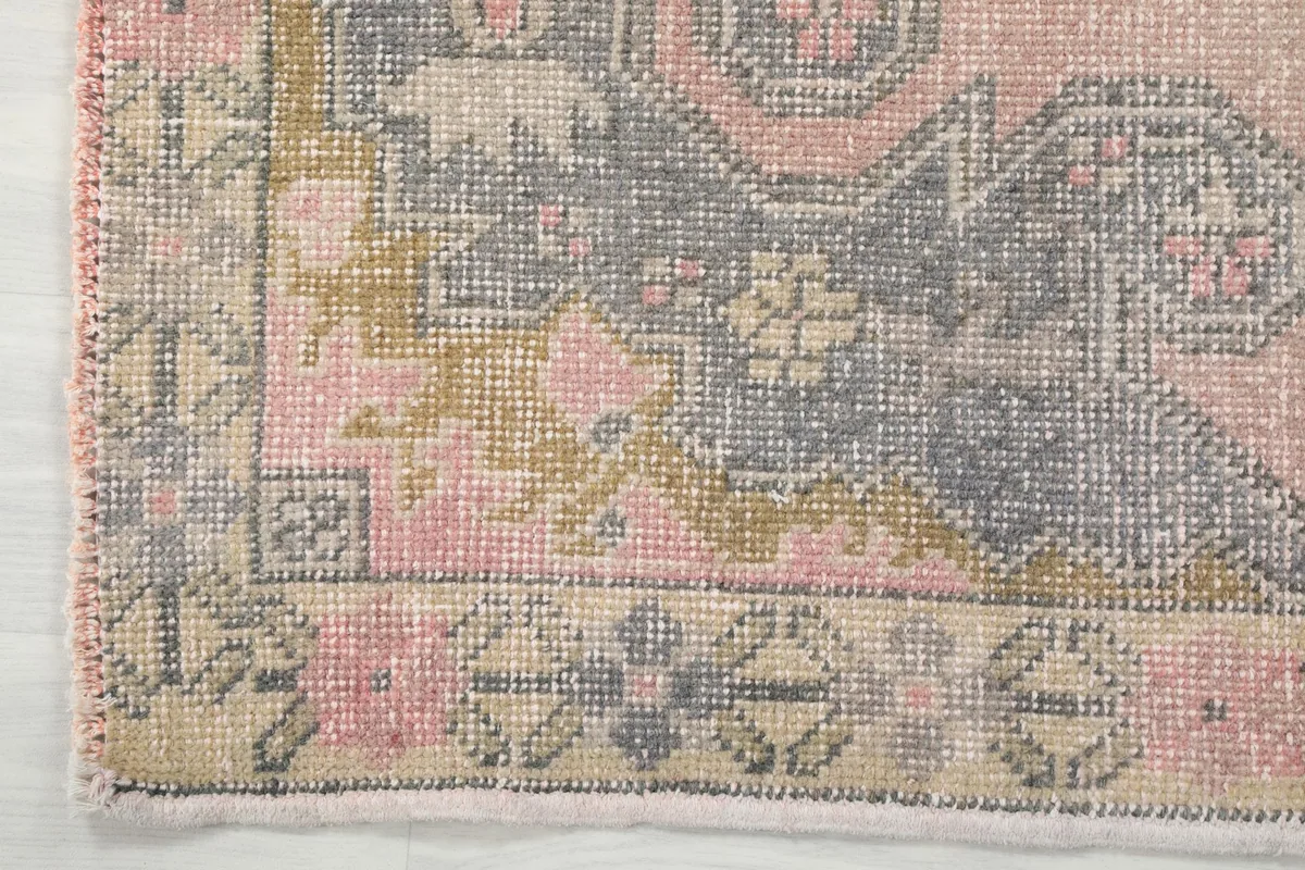 Detailed view of a corner of the rug, showing the outer border design and fringe.