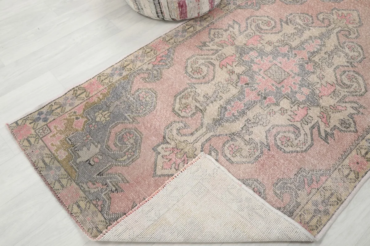 Corner of the vintage rug folded back to reveal the cotton foundation and the reverse side.