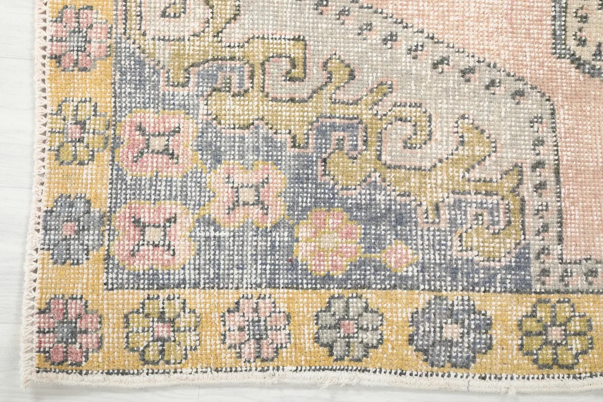 Corner detail of the rug, showcasing the yellow border with floral patterns and the geometric field