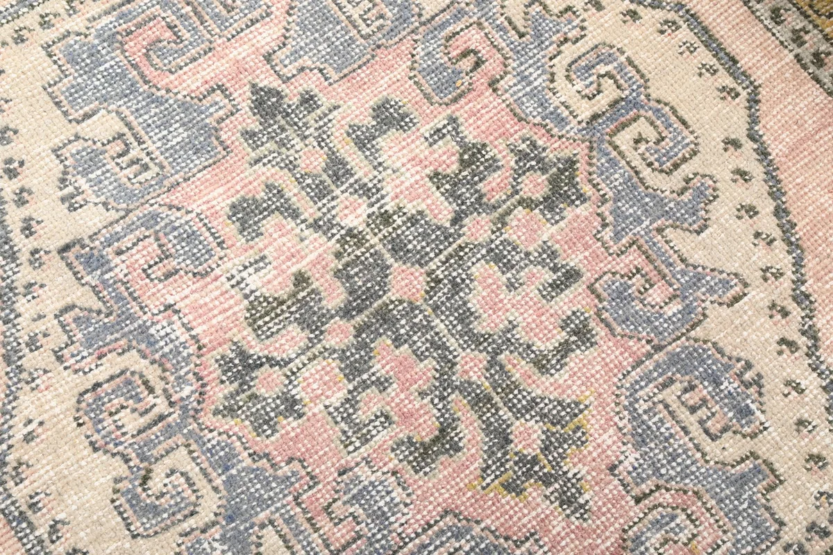 Detailed view of the wool pile, showing the texture and faded colors of the medallion design