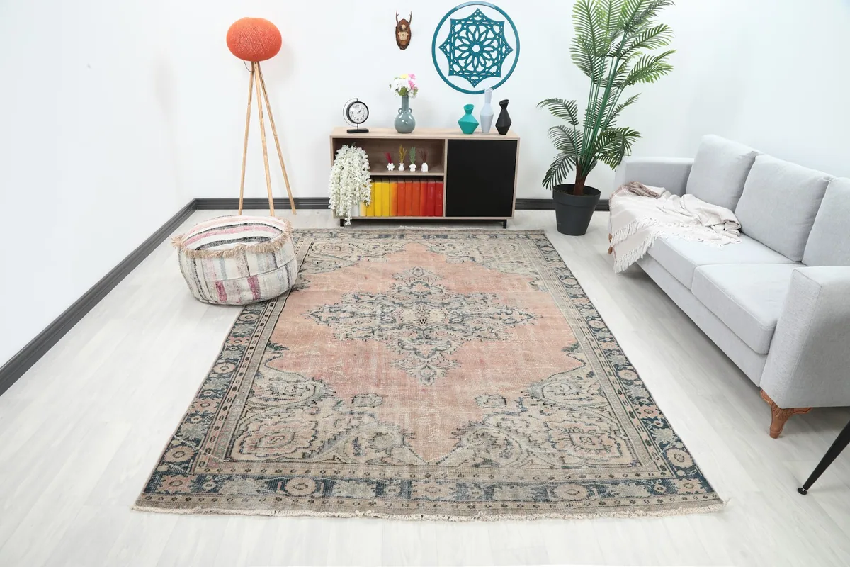 Rose and navy vintage rug displayed in a living room setting with a light gray sofa and modern decor