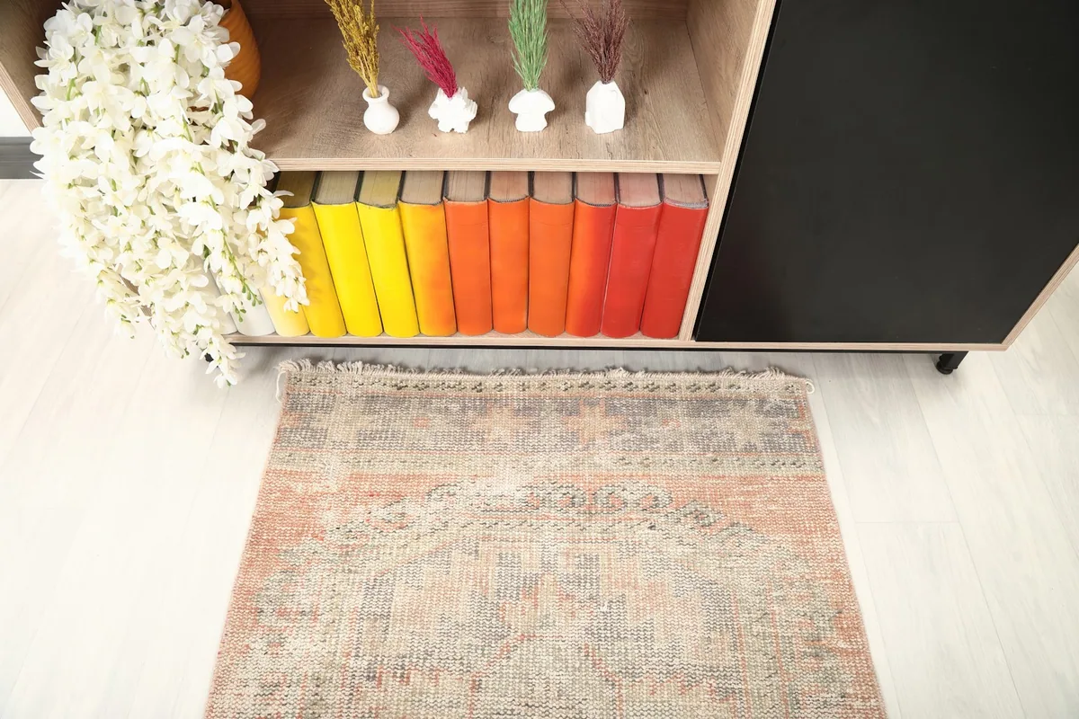 Detail of the runner rug's pattern and color variation at one end, near a bookshelf.