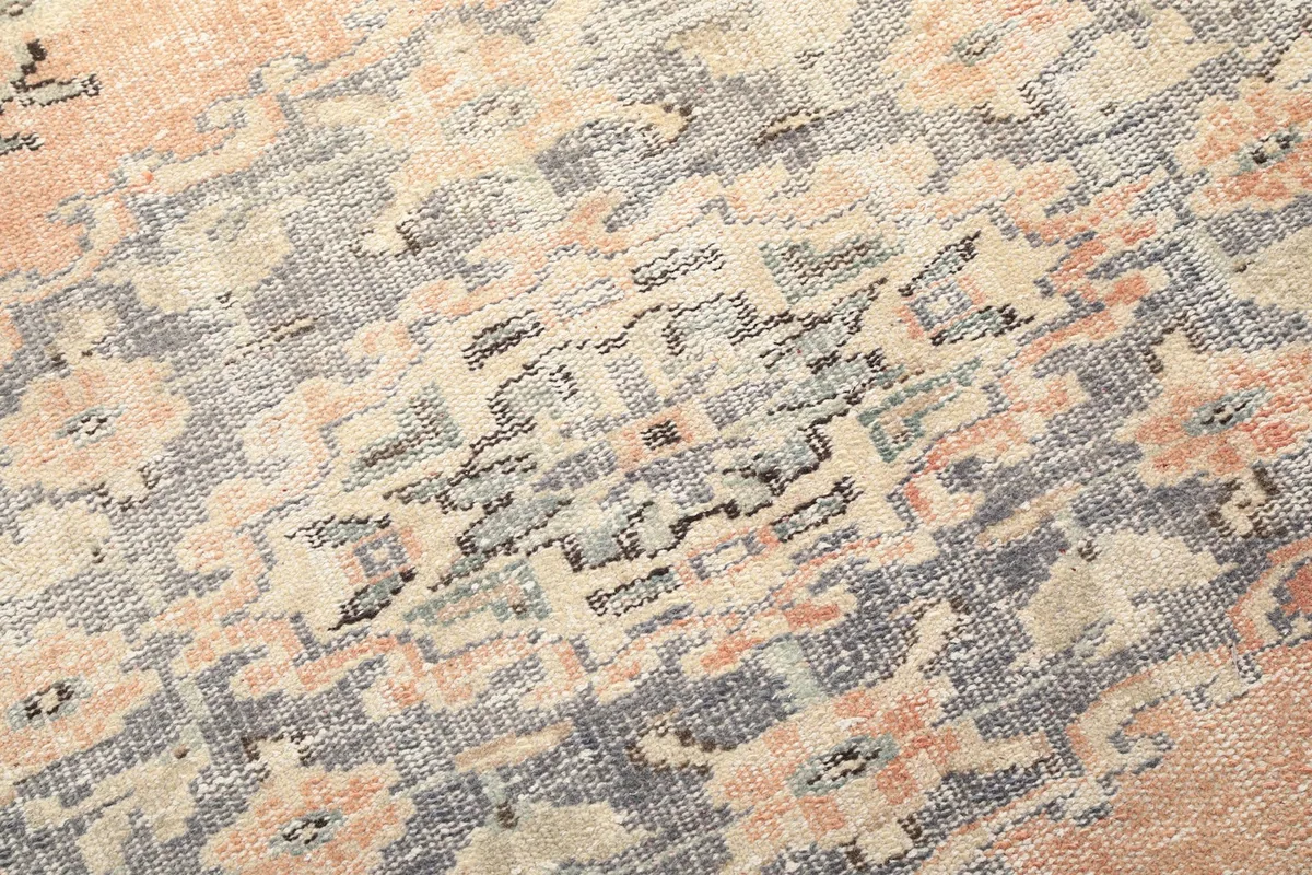Close-up of the distressed gray and beige geometric patterns within the rug's border