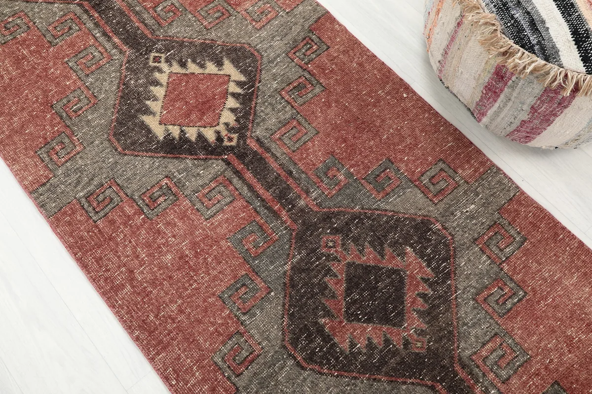 Close-up of the central geometric motifs and color variations within the rust and charcoal runner.