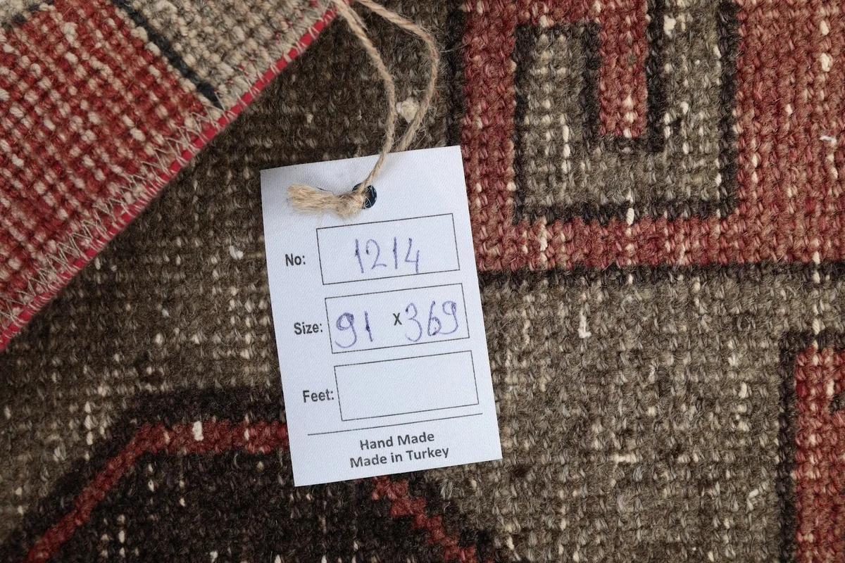 Close-up of the rug's label, indicating its hand-made origin and dimensions in centimeters.