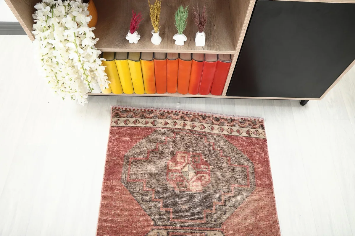 Top-down view of one end of the runner rug, extending from under a cabinet with colorful books.