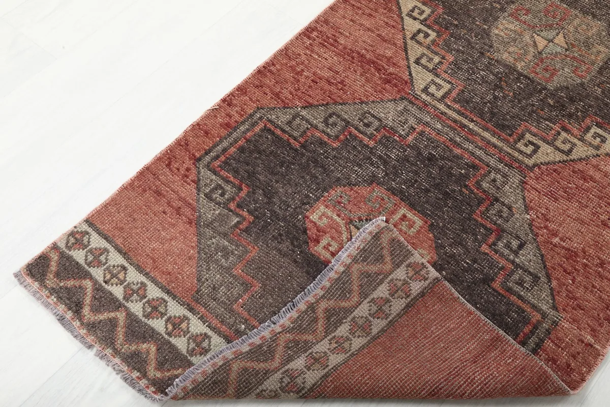 Corner of the runner rug folded to show the pile and the reverse side of the border pattern.
