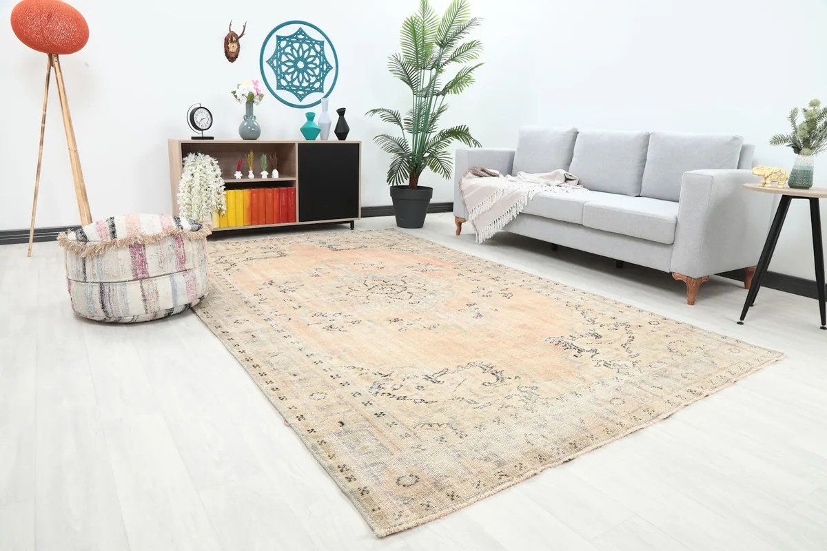 Angle view of the rose and beige vintage rug in a living room, showing its scale with a sofa
