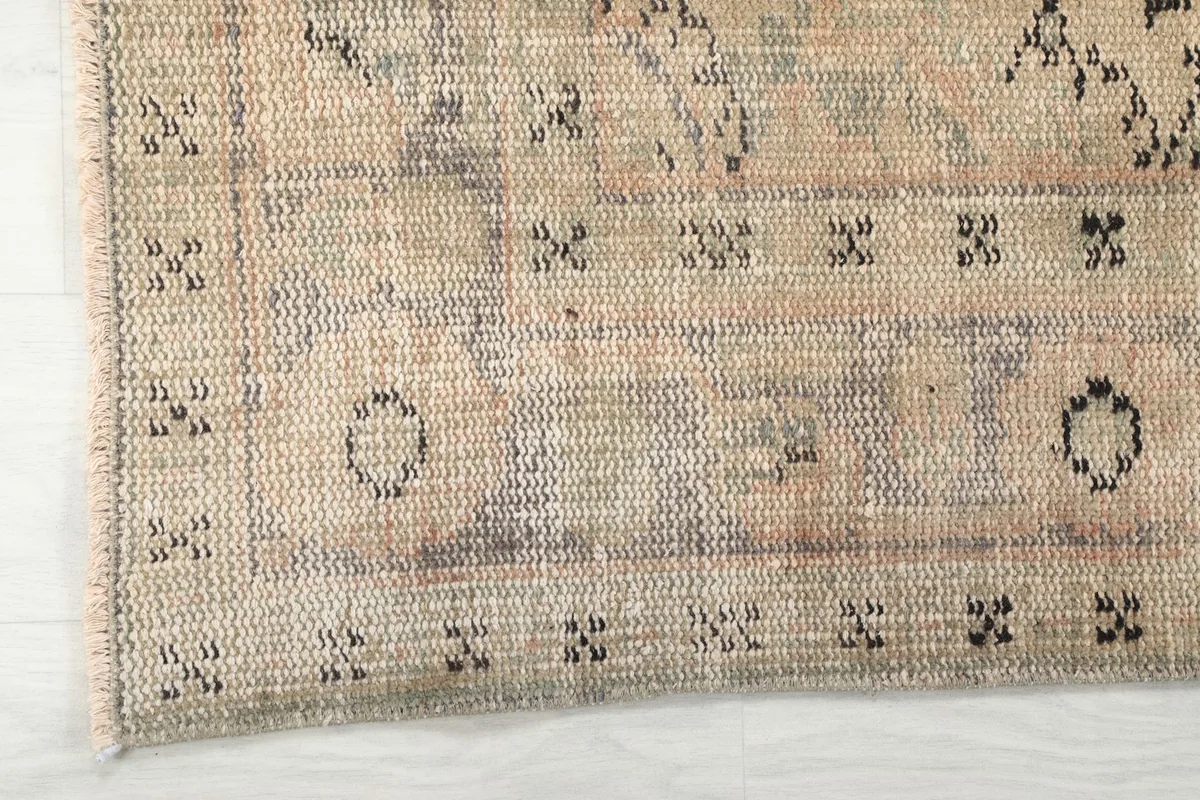 Close-up view of the rug's beige border and edge with subtle geometric patterns