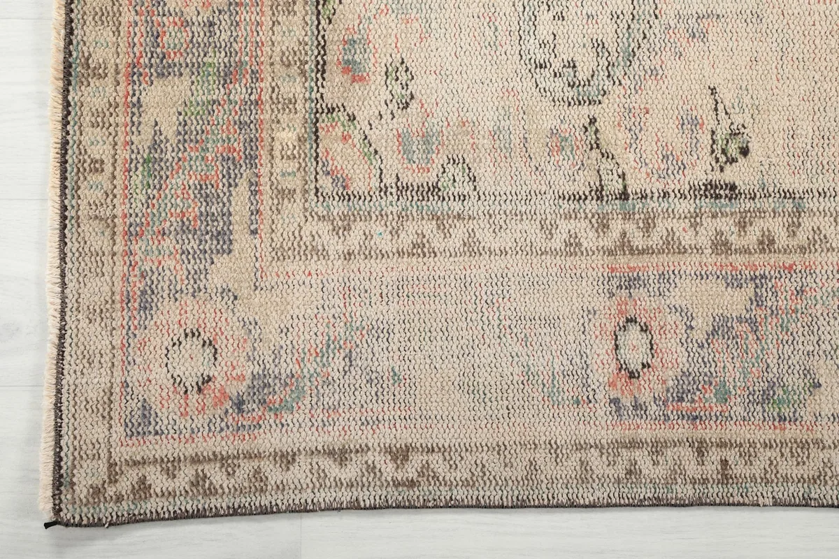 Detailed view of the rug's intricate border design with rose, gray, and green accents