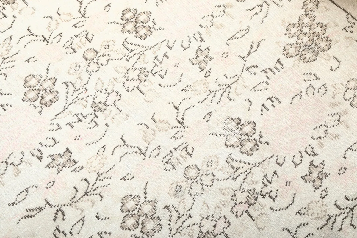 Macro view of the rug's low pile and intricate gray floral and geometric designs