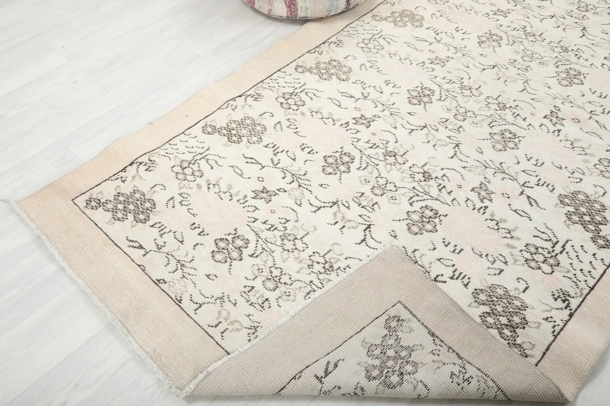 View of the rug's corner folded back, showing the back of the weave and pile