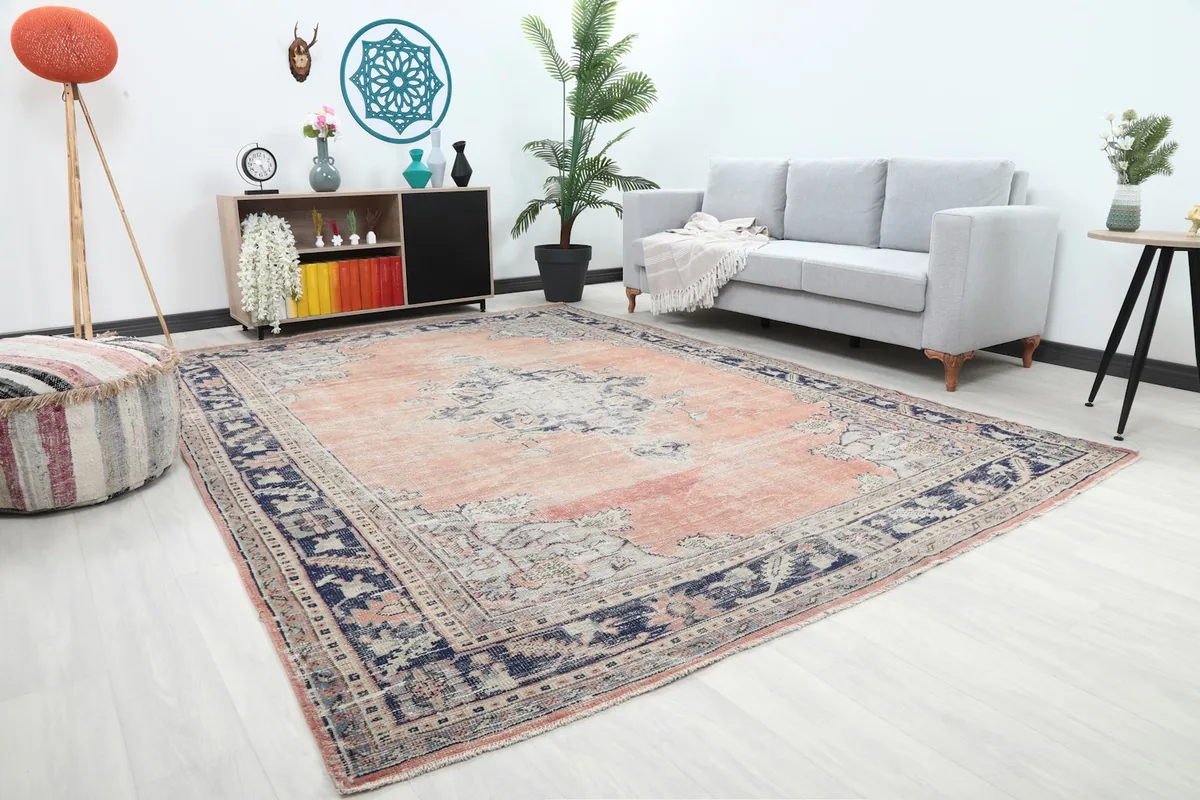 Angle view of the rose and navy rug in a living space with a gray sofa.