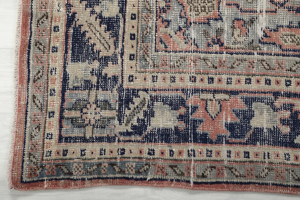 Close-up of the rug's navy and beige border with intricate patterns and subtle wear.