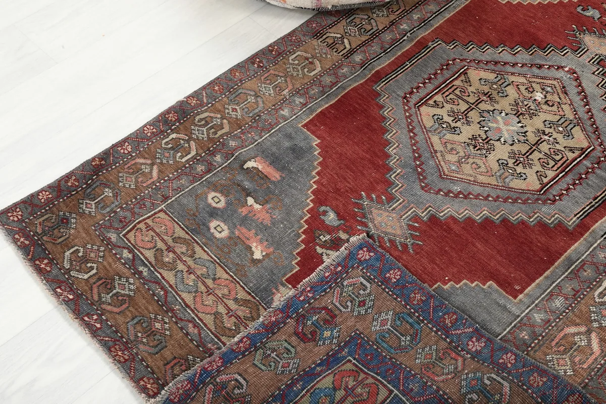Corner view of the rug, showing the blend of red, gray, and tan colors with visible texture