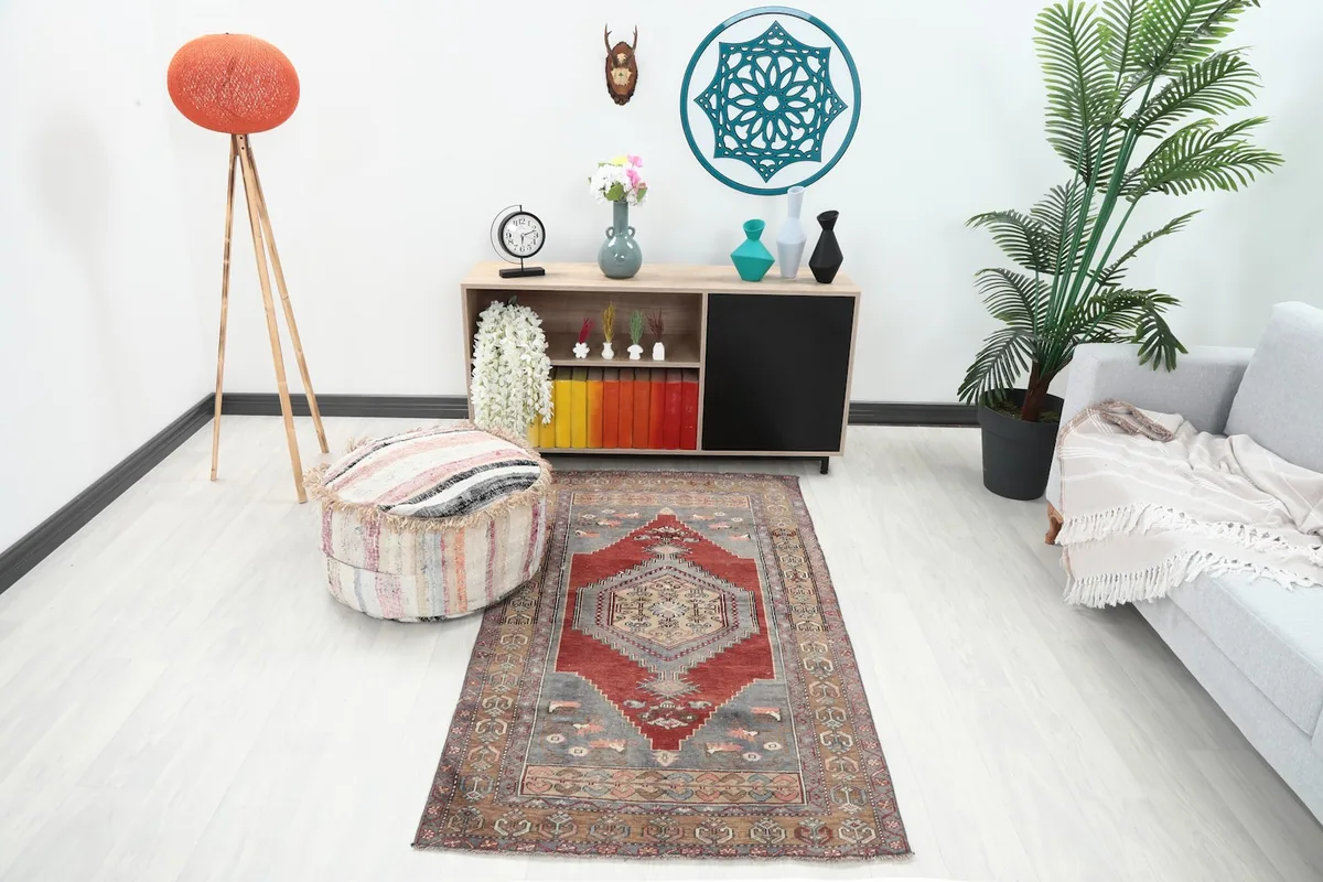 Red tribal rug displayed in a bright living space with a light gray sofa and modern decor