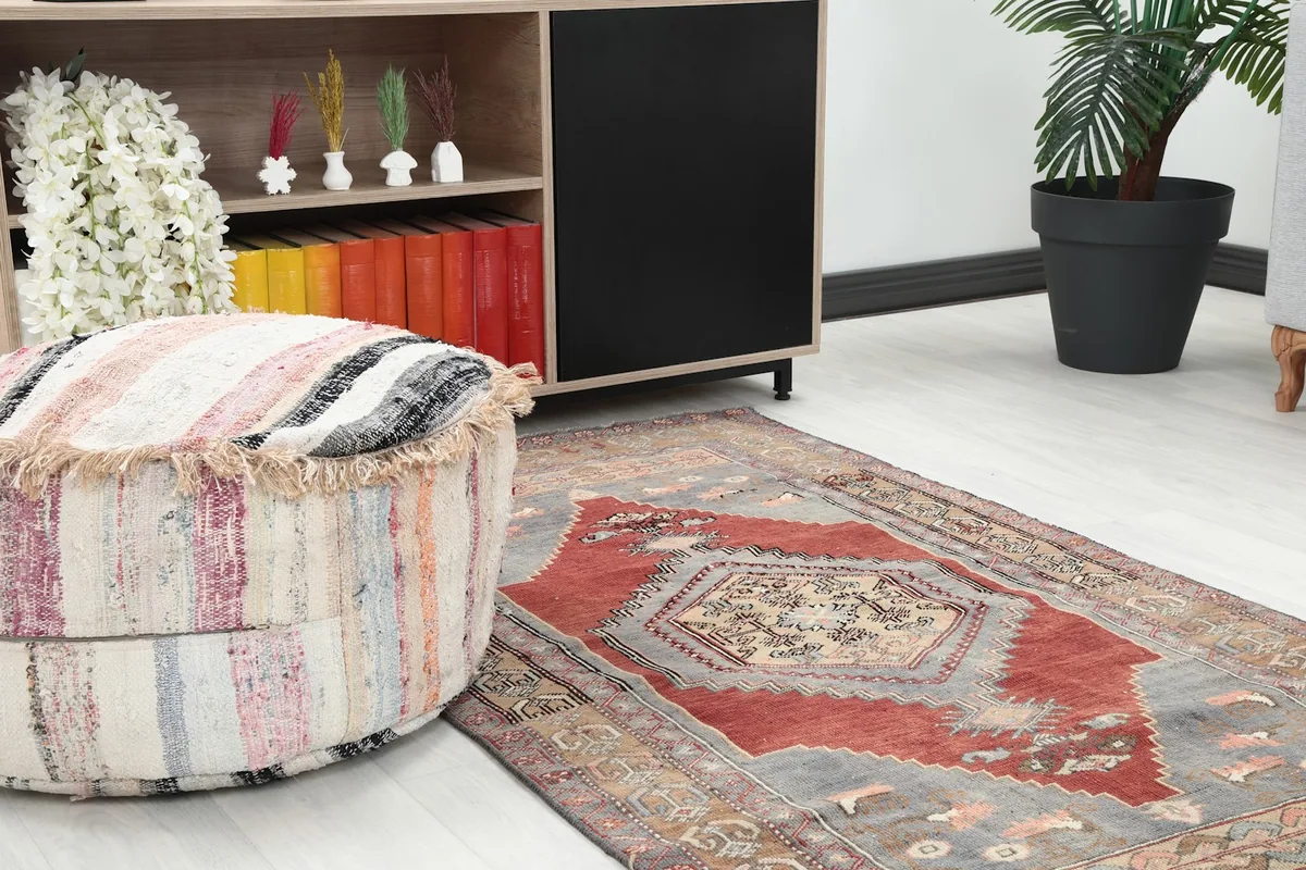 Close-up of the rug's pattern and texture, showing it placed next to a striped pouf and shelving