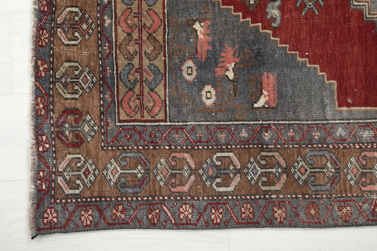 Close-up of the rug's multi-layered border with various geometric and stylized motifs in tan and brown