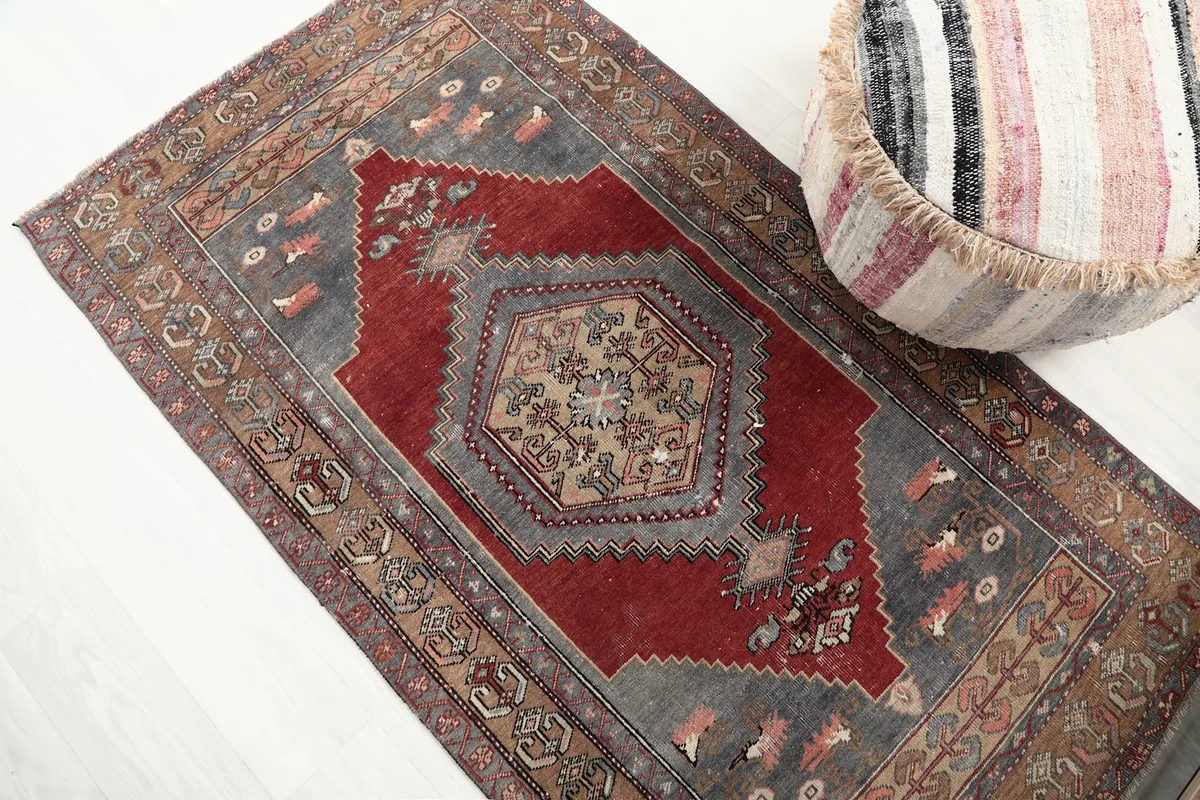 Overhead view of the rug's central medallion and tribal motifs, with a pouf in the corner