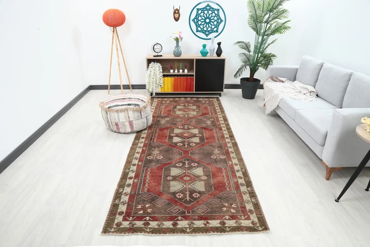 Vintage red and brown runner rug displayed in a modern hallway with a light gray sofa and wooden furniture