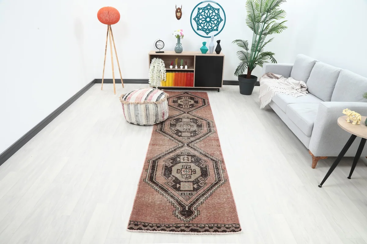 Rose and brown runner rug in a modern living room setting with a light gray sofa and wooden furniture