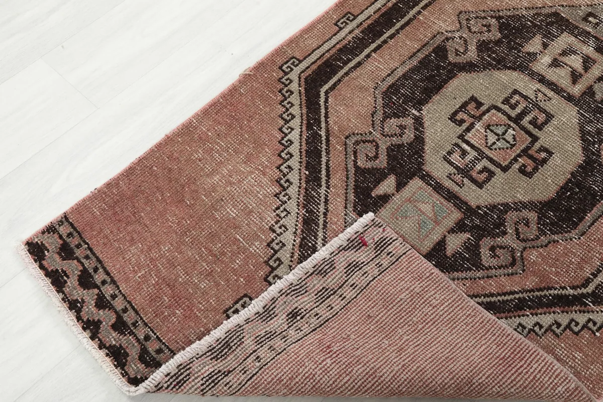 Folded corner of the runner rug revealing the cotton foundation and the reverse side of the pattern