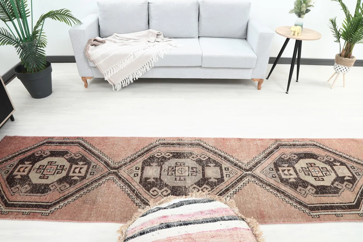 Overhead view of the rose and brown runner rug in a room, showing its length in front of a sofa